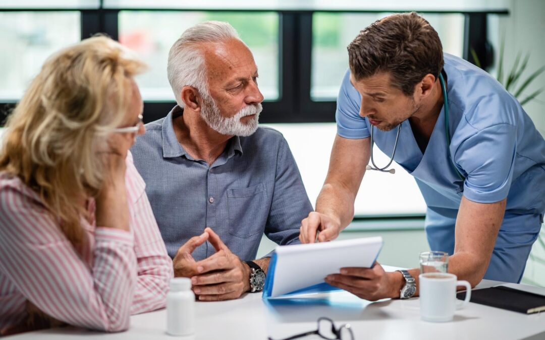 A healthcare professional in blue scrubs is attentively explaining documents to a senior couple at a table - https://www.johnsoncitymedicare.com/